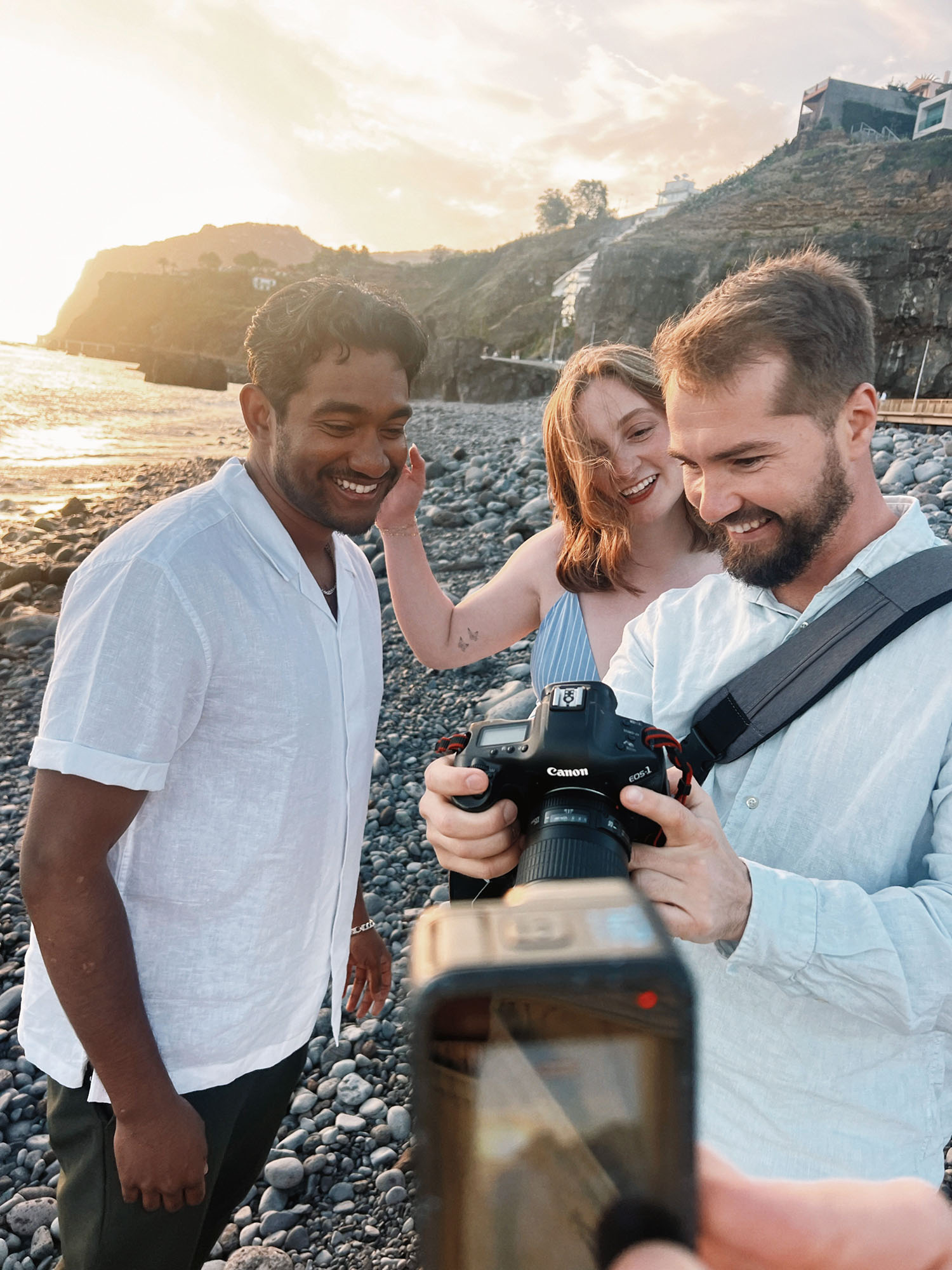 Mihail Zhelezniak showing photos to clients on a rocky beach in Madeira at sunset